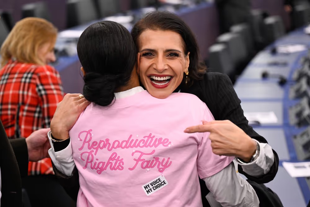 Abir al-Sahlani kramas om av kvinna i rosa tröja med texten ”Reproductive rights fairy”.
