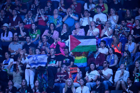 Blått ljus på publik där både en israelisk och palestinsk flagga hålls upp.